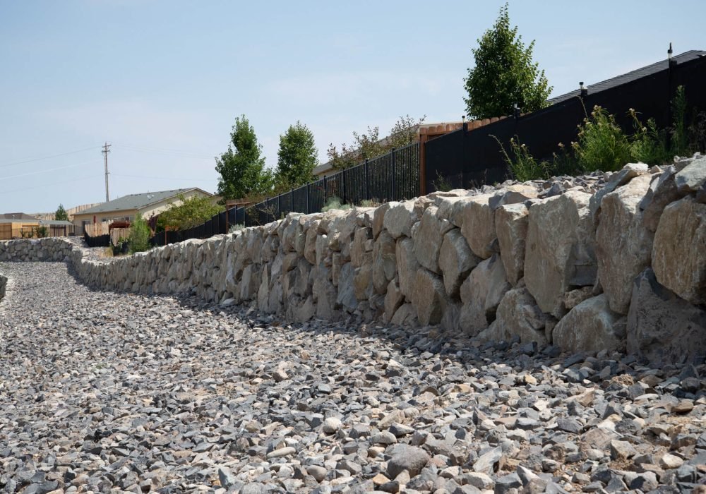 Engineered drystack boulder retainer wall for commercial or residential.